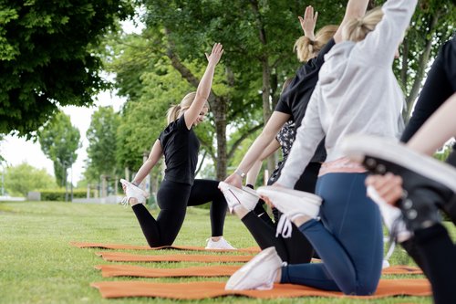 Azubi-Gesundheit. Foto: E. Fromme-Klute-Fotografie Das Bild zeigt mehrere Personen auf einer Rasenfläche bei einer Dehnübung. Foto: E. Fromme-Klute-Fotografie