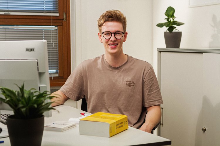Ein junger Mann sitzt an seinem Arbeitsplatz und hat ein Buch für Soziale Arbeit vor sich liegen. Foto: Thomas Grimm