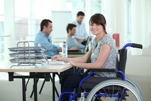 Junge Frau im Rollstuhl arbeitet am Laptop. Foto: © auremar - Fotolia.com
