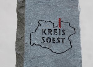 Ehrenamtspreis Kreis Soest - Steinblock. Foto: Thomas Weinstock/Kreis Soest Auf der Vorderseite der Stele sind die Kreisgrenzen und das Logo des Kreises Soest abgebildet, auf der Rückseite befindet sich eine Inschrift auf einem Edelstahlschild. Foto: Thomas Weinstock/Kreis Soest