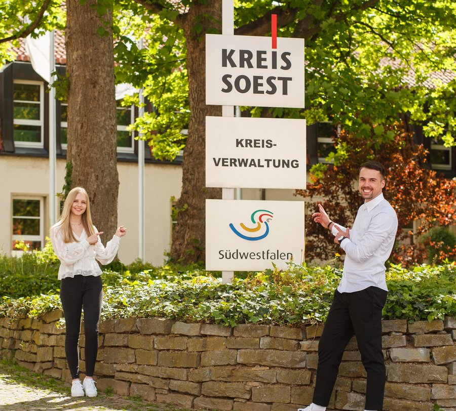 Zwei Studierende posieren vor den Schildern vor dem Haupteingang. Foto: M. Petrilli