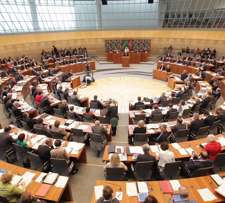 Eine Fotoaufnahme, die bei einer Sitzunng des Landtages gemacht wurde. Die Landtagsmitglieder sitzen an ihren Tischen. Foto: Landtag NRW/Bernd Schälte