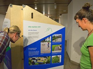 Bei Personen betrachten den Aufsteller zur Ausstellung „Aufgepasst. Angepasst!“. Foto: Kira Hönicke/ Kreis Soest