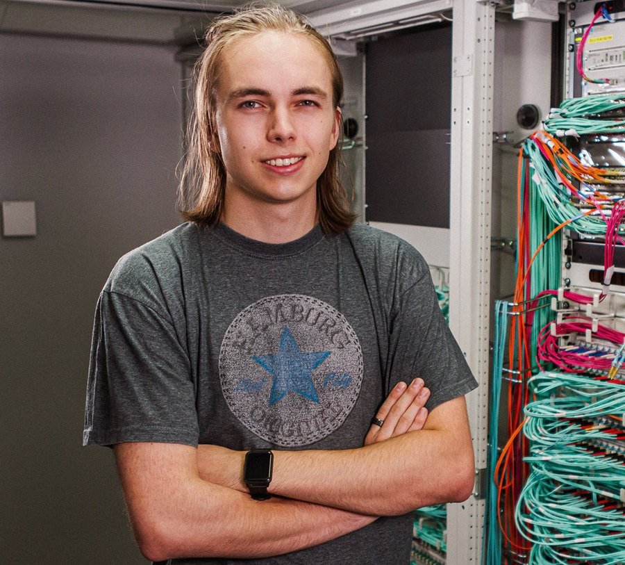 Ein Mann steht in einem Serverraum vor vielen bunten Kabeln. Foto: Thomas Grimm