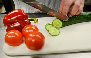 Belehrungen_Lebensmittelberufe. Foto: Mathias Keller/Kreis Soest Hände, die eine Gurke auf einem Brett schneiden. Foto: Mathias Keller/Kreis Soest
