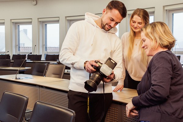 Drei Personen schauen auf die Fotos einer Spiegelreflexkamera. Foto: Thomas Grimm