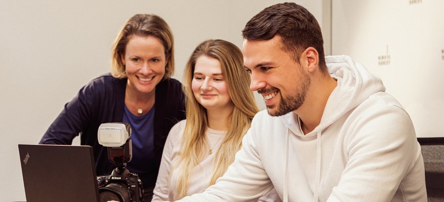 Volontär für die Presse- und Öffentlichkeitsarbeit. Foto: Thomas Grimm Eine Person schaut lächelnd auf einen Laptop. Zwei weitere Personen schauen ebenfalls auf den Laptop. Foto: Thomas Grimm