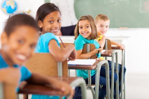 Unterricht in der Grundschule. Foto: © michaeljung - Fotolia Grundschulkinder unterschiedlicher Herkunft sitzen im Klassenzimmer und lächeln in die Kamera. Foto: © michaeljung - Fotolia