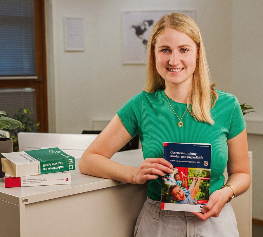 Eine junge Frau steht mit Büchern zum Jugendhilferecht vor einem Sideboard. Foto: Thomas Grimm