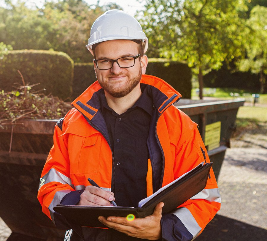 Umweltoberinspektoranwärter. Foto: Thomas Grimm Ein Mann steht in Dienstkleidung vor einem Abfallcontainer. Foto: Thomas Grimm