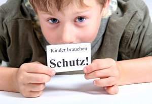 Junge mit Zettel "Kinder brauchen Schutz!". Foto: © Yvonne Bogdanski - Fotolia.com  