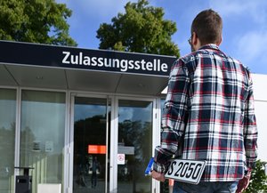 Mann mit Kennzeichen in der Hand geht zur Zulassungsstelle in Soest. Foto: Judith Wedderwille/Kreis Soest