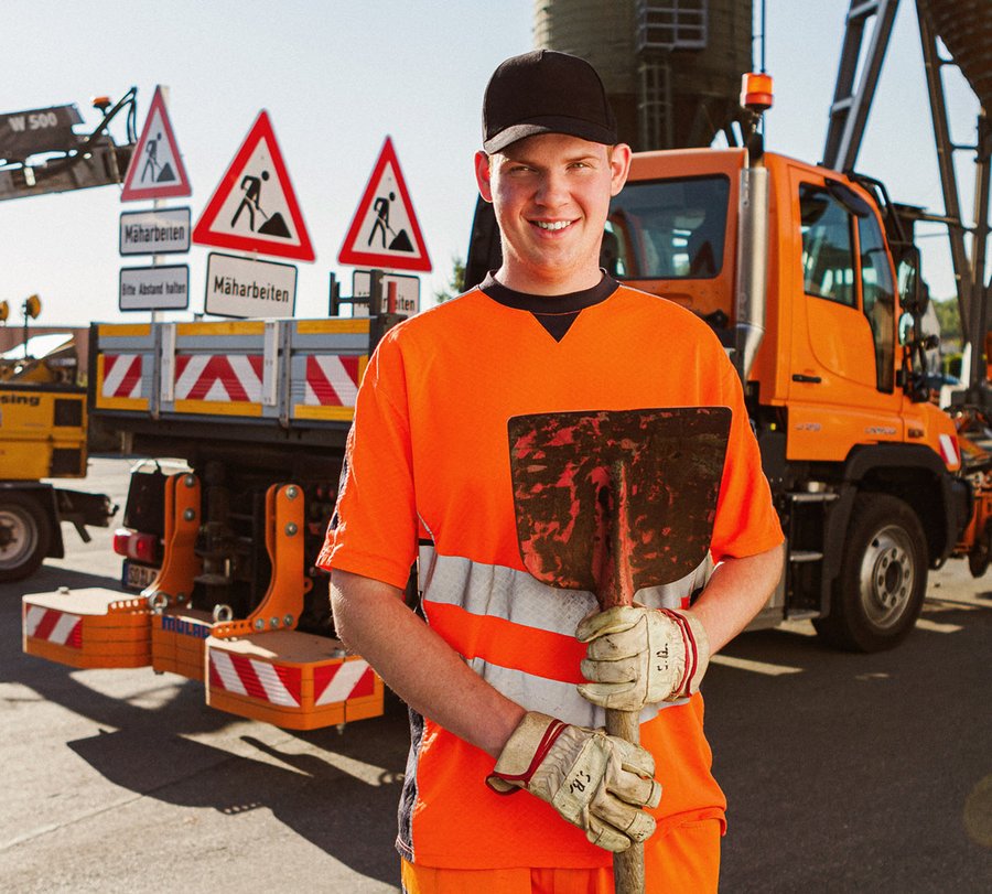 Straßenwärter. Foto: Thomas Grimm Ein junger Mann steht mit einer Schüppe vor einem Laster des Baubetriebshofs. Foto: Thomas Grimm