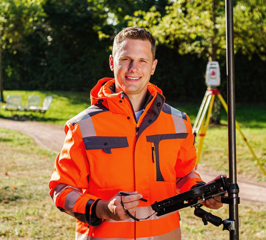 Vermessungsoberinspektoranwärter. Foto: Thomas Grimm Ein Mann steht mit einem Messgeräten und einem Tablet im Grünen. Foto: Thomas Grimm
