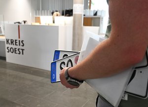 Eine Person hält Kfz-Kennzeichen und Dokumente unter seinem Arm. Foto: Judith Wedderwille/ Kreis Soest