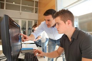 Mann zeigt Jugendlichen etwas am Monitor. Foto: © goodluz - Fotolia.com