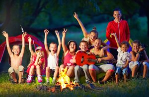 Kinder vor Zelten mit einer Betreuerin. Foto: © olesiabilkei - Fotolia