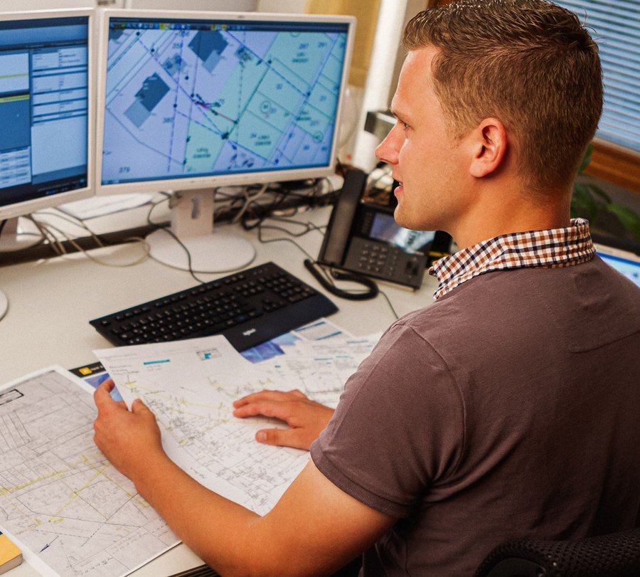 Ein Mann, der Unterlagen vor sich liegen hat, schaut auf ein Vermessungsprogramm auf seinem Dienstrechner. Foto: Thomas Grimm