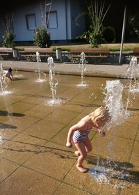 Ein Kind spielt mit einer Wasserfontäne. Foto: Anja Berg/ Kreis Soest
