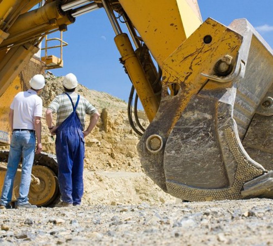 Arbeiter vor einem großen Bagger in einem Steinbruch. Foto: © fineart-collection - Fotolia.com