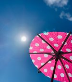 Ein pinker Cocktailschirm mit Punkten ist im Vordergrund zu sehen. Die Sonne scheint am Himmel. Foto: Judith Wedderwille/ Kreis Soest