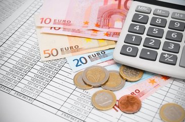 Geld und Taschenrechner auf einer gedruckten Tabelle. Foto: © artem_ka - Fotolia.com