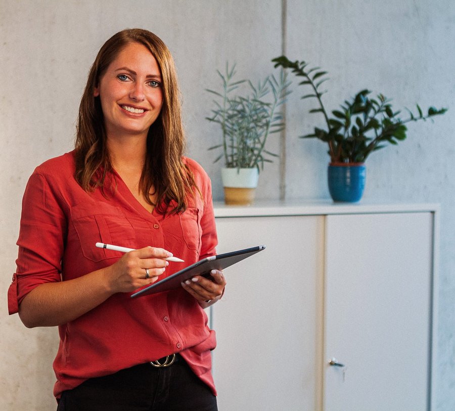 Eine junge Frau steht mit iPad vor einer Betonwand. Foto: Thomas Grimm