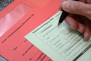 Hand mit Kugelschreiber über dem Formular einer Todesbescheinigung. Foto: Judith Wedderwille/Kreis Soest