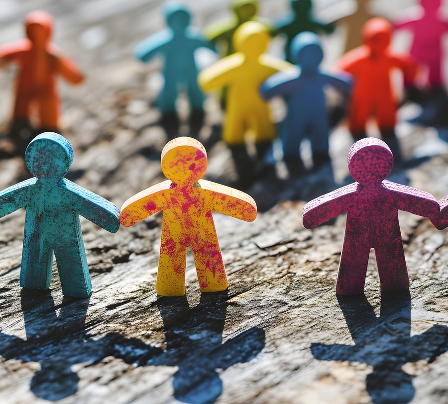 Farbige Holzmännchen, die sich an der Hand fassen und im Kreis stehen. Foto: Augusto/stock.adobe.com