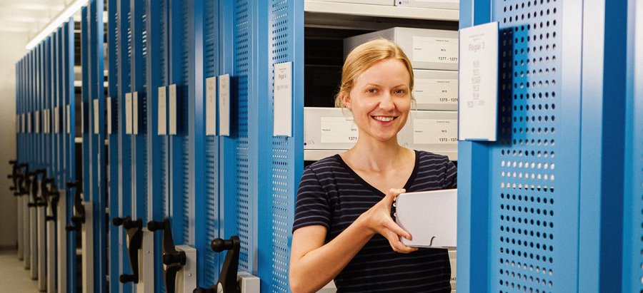 Eine Frau zieht etwas aus dem Lagerschrank im Kreisarchiv hervor. Foto: Thomas Grimm