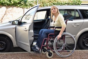 Rollstuhlfahrerin steigt in Auto ein. Foto: © Dan Race - Fotolia.com