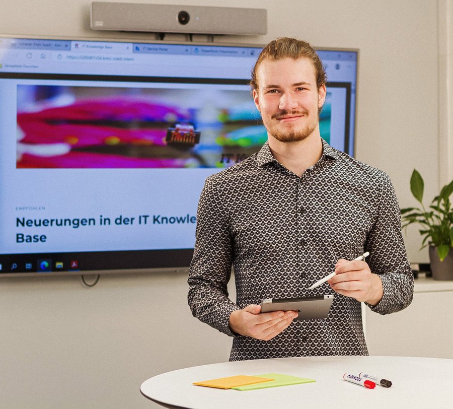 Ein Mann hält ein iPad und steht vor einem Flachbildschirm. Foto: Thomas Grimm