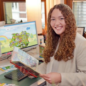 Eine Frau mit lockigen Haaren schaut sich eine Broschüre an und lächelt in die Kamera. Foto: Thomas Weinstock/ Kreis Soest